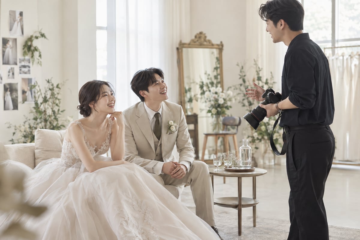 웨딩 촬영 중 잠시 앉아 쉬며 촬영자와 다음 장면을 이야기하는 신랑 신부